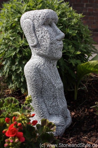Moai Gartenfigur aus Stein in der Seitenansicht, aufgestellt in einem Blumenbeet.