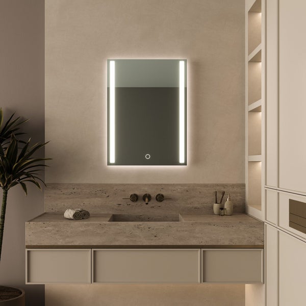 Rechteckiger Badezimmerspiegel mit LED Beleuchtung und Touch Schalter über einem Stein Waschbecken in einem modernen Badezimmer.