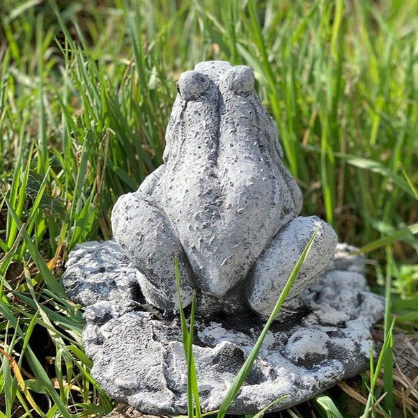 Steinfigur Frosch aus wetterfestem Kunststein für die Gartendekoration auf einer Steinplatte sitzend