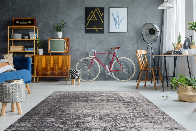 Grauer Kurzflor-Teppich mit Vintage-Muster in einem modern eingerichteten Wohnzimmer mit Retro-Möbeln und einem Fahrrad.