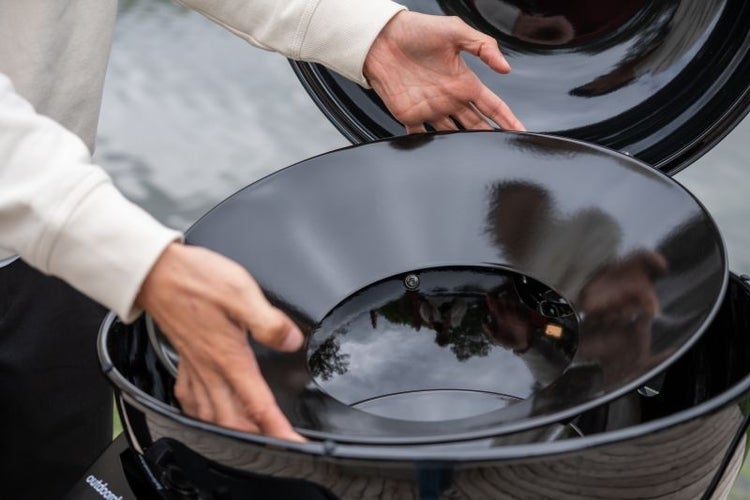 Einsetzen eines emaillierten Trichters in einen Outdoorchef Kugelgrill.