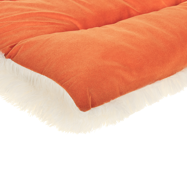 Detailansicht eines weichen Hundekissens aus orangefarbenem Stoff mit weißem Plüschrand.