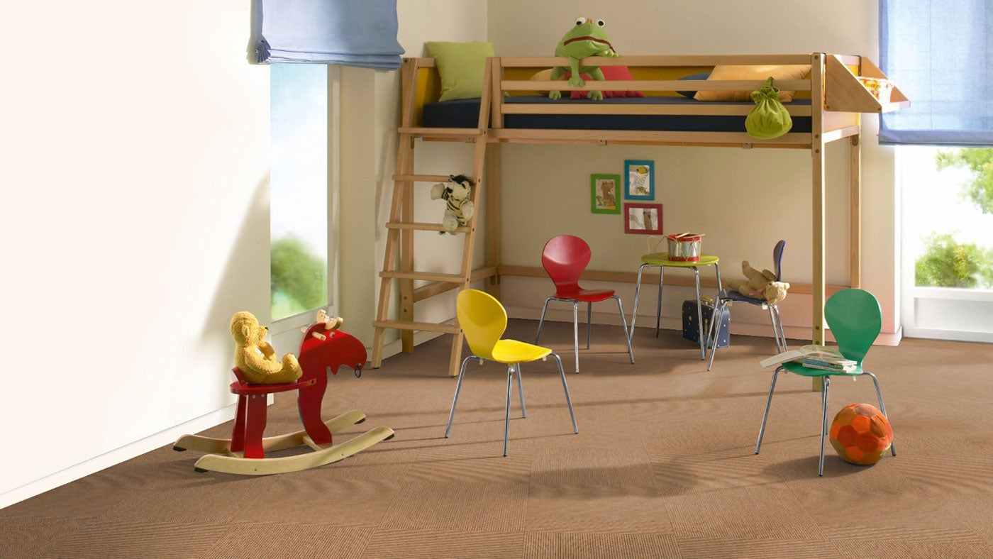 Helles, geräumiges Kinderzimmer mit Hochbett aus Holz, bunten Stühlen und gemusterten braunen Teppichfliesen auf dem Boden.