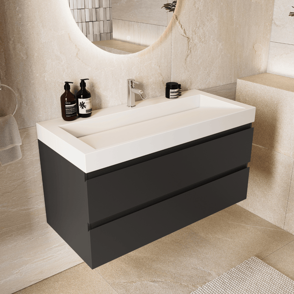 Helles, modernes Badezimmer mit wandhängendem anthrazitfarbenem Waschtischunterschrank, zwei Schubladen und weißem Waschbecken vor Steinwänden.