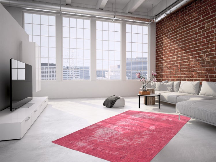 Helles Loft-Wohnzimmer mit Ziegelwand, weißem Sofa und pinkem Teppich im Vintage-Stil auf hellem Betonboden.