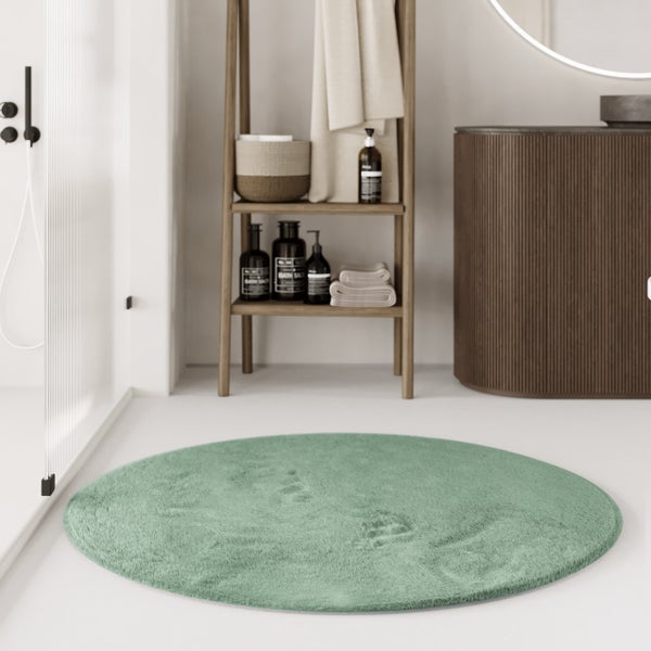 Runder Badteppich in einem hellen Badezimmer mit holzfarbenem Regal und geriffeltem Unterschrank.