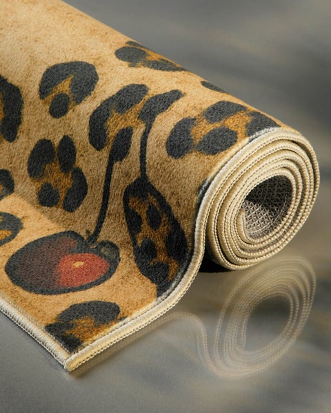 Zusammengerollter Teppich mit Leopardenmuster und Kirschenmotiv.