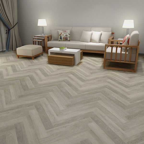 Wohnzimmer mit hellgrauem Fischgrät-Vinylboden, Sofa, Sessel und Couchtisch.