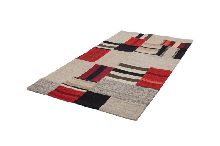 Rechteckiger, bunter Webteppich im Patchwork Design mit verschiedenen Quadraten und Streifenmustern.