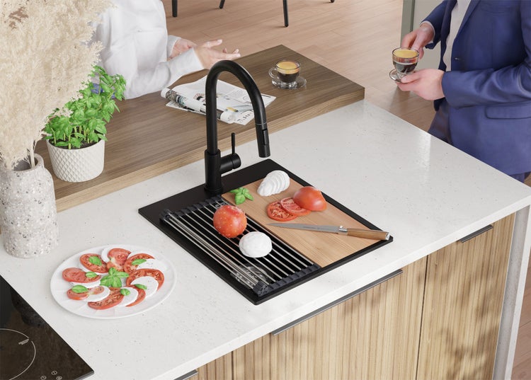 Küchenszene mit Spüle, Armatur, Schneidebrett, Tomaten, Mozzarella und einem zubereiteten Caprese Salat.