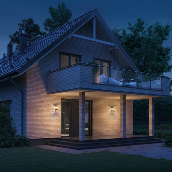 Zweigeschossiges Einfamilienhaus mit Ziegelfassade, Balkon und Terrassenbeleuchtung bei Nacht