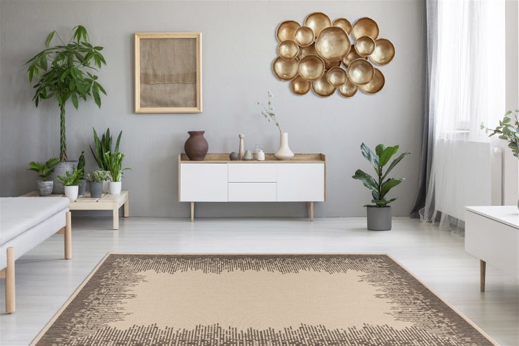 Moderner Wohnraum mit beige-braunem Teppich mit Pixel-Randmuster, weißem Sideboard, Wanddekoration aus Gold-Schalen und Zimmerpflanzen.