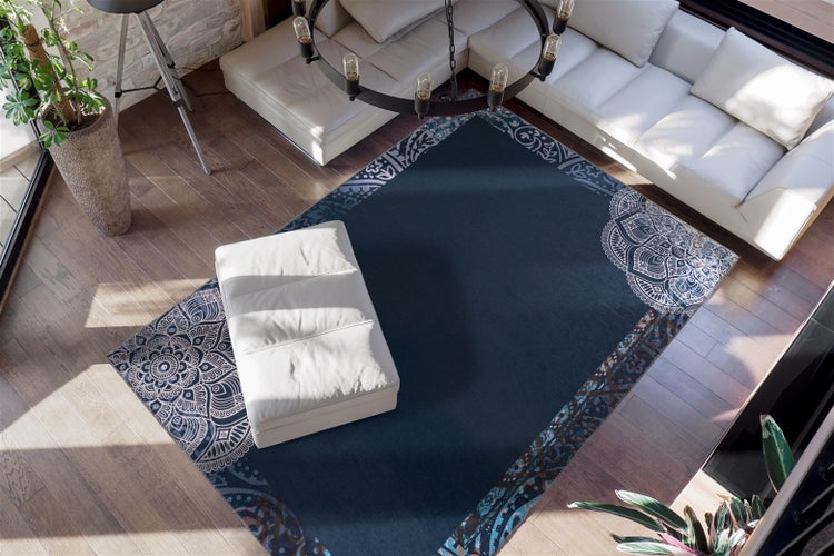 Dunkelblauer Teppich mit Mandala-Muster auf Holzboden, kombiniert mit weißem Sofa und Hocker in einem hellen, modernen Wohnzimmer.