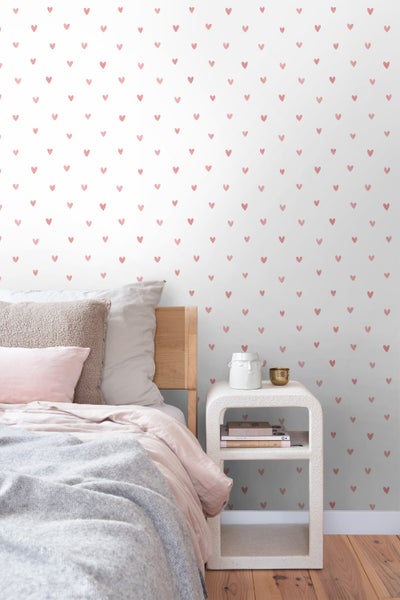 Schlafzimmer mit Bett und Wandtapete mit Herzmuster