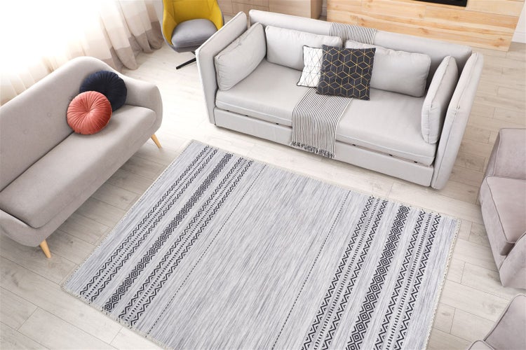 Helles Wohnzimmer mit grauem Teppich mit geometrischem Muster, zwei Sofas und hellem Holzboden.