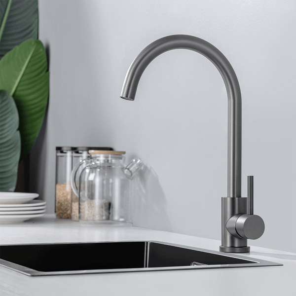 Moderne Küchenarmatur mit hohem schwenkbarem Auslauf und Einhebelmischer auf einer Küchenspüle mit Pflanzen und Vorratsgläsern im Hintergrund.