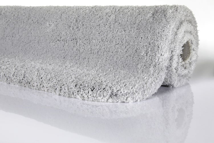 Hochflor-Teppich in Grau, weich, aufgerollt.
