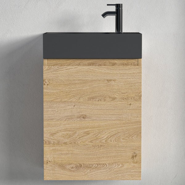 Ein Waschtisch mit Unterschrank in Eichenoptik und einem montierten Wasserhahn an der Wand montiert.