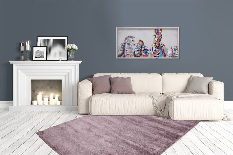 Modernes Wohnzimmer mit weißem Sofa, lila Hochflor-Teppich, weißem Kaminumbau und einem bunten Zebra-Gemälde an der Wand.