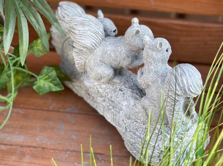 Gartenfigur aus Kunststein in Form von drei Eichhörnchen auf einem Baumstamm als dekorative Gartendekoration