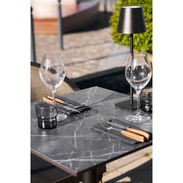 Gedeckter Tisch mit Tischleuchte, Weingläsern und Besteck für den Außenbereich.