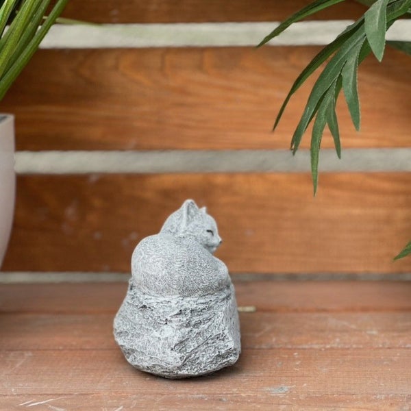 Dekorative Katzenfigur aus Stein in sitzender Position als Gartendekoration.