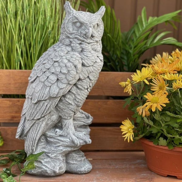Dekorative Gartenfigur einer Eule aus Stein, stehend auf einem Felsvorsprung, als Gartendekoration geeignet.