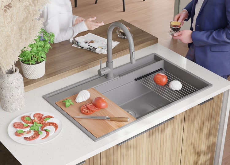 Graue Spüle mit Abtropfgestell, Armatur und Zubehör auf einer Küchentheke.