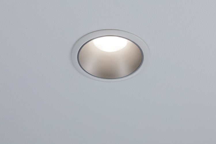 Eingebauter Deckenspot mit runder Blende und leuchtendem Lichtkegel.