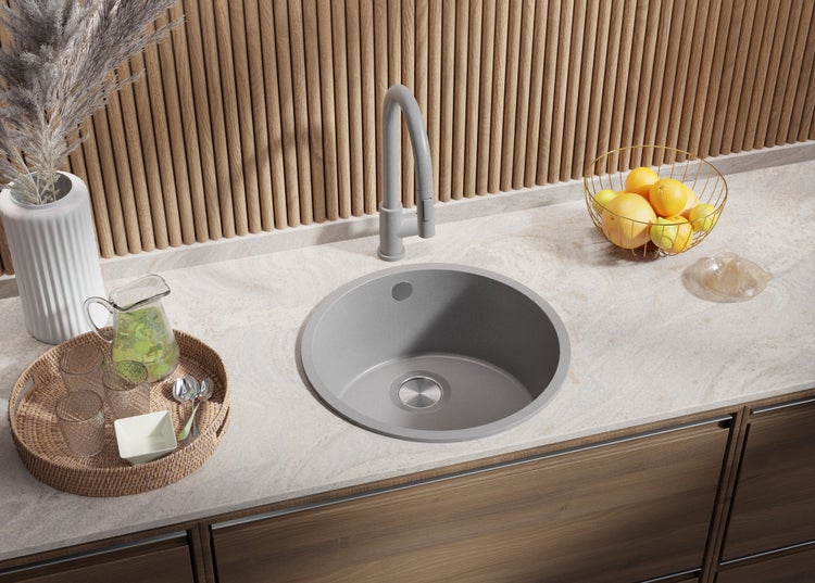 Küchenszene mit runder Spüle, Armatur und dekorativen Elementen auf einer Arbeitsplatte.