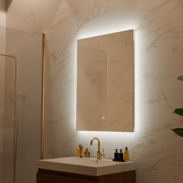 Moderner Badezimmerspiegel mit LED Beleuchtung und Touch Sensor über einem Waschbecken mit goldener Armatur vor einer Marmorwand.