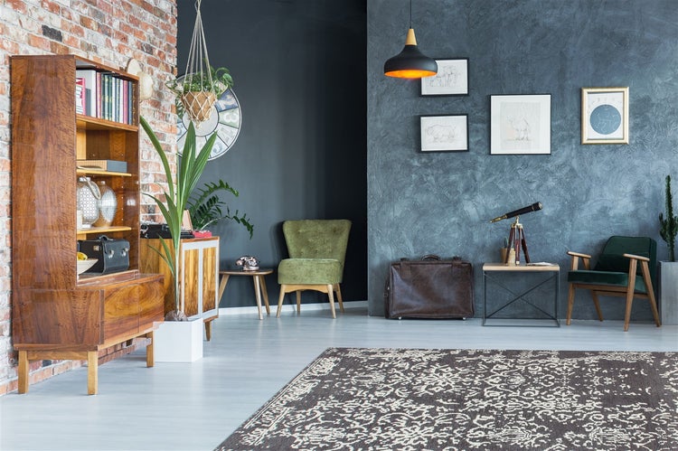 Wohnzimmer mit Backsteinwand, Holzmöbeln, grünen Sesseln, großem gemustertem Teppich und dekorativen Elementen. Helle, organisierte Atmosphäre.