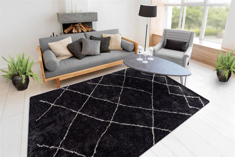 Hochflor-Teppich mit Rautenmuster in einem modern eingerichteten Wohnzimmer mit grauem Sofa, Sessel und Couchtisch.