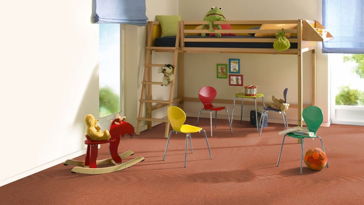 Hell eingerichtetes Kinderzimmer mit strukturierten Teppichfliesen, hölzernem Hochbett und bunten Stühlen.