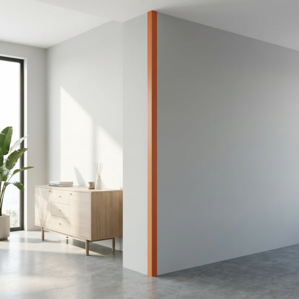 Moderne Wand mit orangefarbenem Eckprofil in einem minimalistisch eingerichteten Raum mit Holzkommode und Zimmerpflanze.