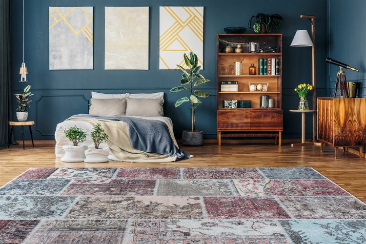 Moderner Teppich im Patchwork-Design in einem stilvoll eingerichteten Schlafzimmer mit dunklen Wänden und Holzmöbeln.