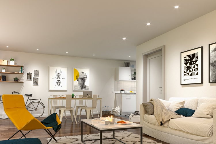 Ein moderner, offener Wohnbereich mit Essplatz, Küche und gemütlichem Sofa, eingerichtet in einem zeitgenössischen, hellen Stil.