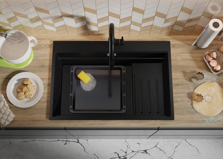 Spüle mit Armatur, Backblech, Schwamm und Küchenutensilien auf einer Küchentheke.