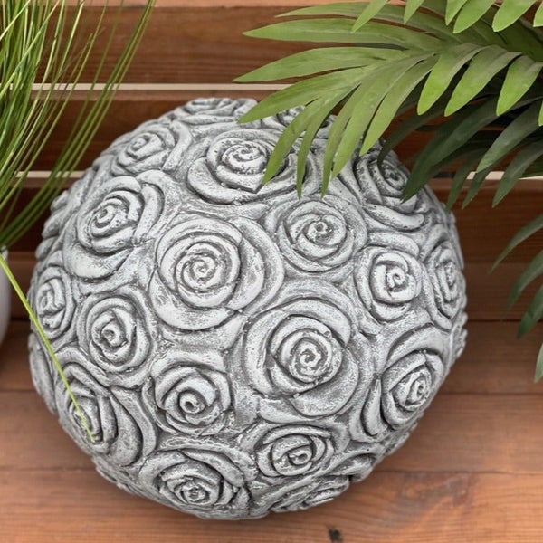 Dekorative Gartenkugel aus Stein in Kugelform mit eingearbeitetem Rosenrelief als Garten- oder Terrassendekoration.