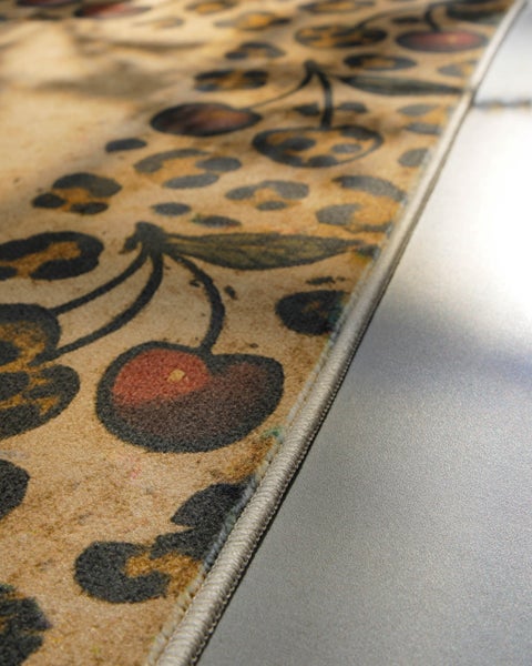 Teppich mit Kirsch- und Leopardenmuster, Detailansicht der gekettelten Kante.