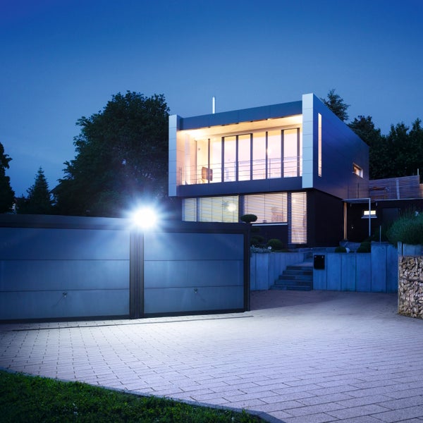 Moderne Villa mit Außenbeleuchtung und beleuchteter Doppelgarage in der Abenddämmerung.