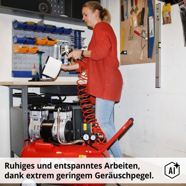 Eine Frau reinigt in einer Werkstatt einen Filter mit Druckluft von einem mobilen Kompressor vor einer organisierten Werkzeugwand.