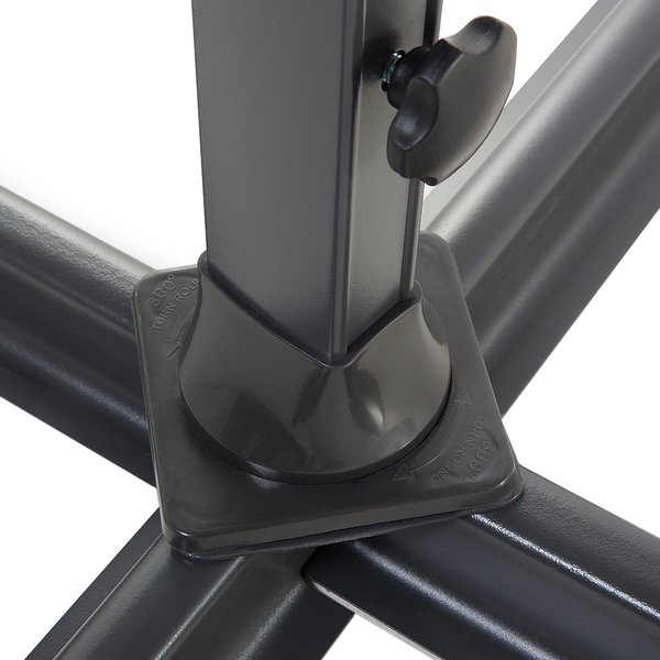 Ampelschirm mit beigefarbenem Bezug über einer weißen Gartenlounge aus Polyrattan auf einer Rasenfläche mit Bäumen im Hintergrund.