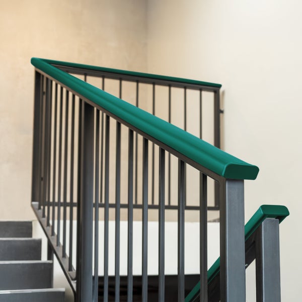 Modernes Treppengeländer aus Metall mit grünem Handlauf und vertikalen Stäben an einer Treppe.