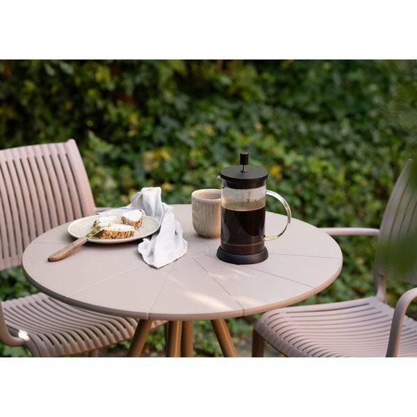 Gartenszene mit Tisch, Stühlen, Kaffeebereiter und Imbiss