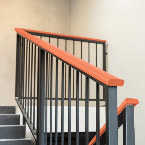 Modernes Treppengeländer aus Metall mit durchgehendem Handlauf für den Innenbereich, montiert an einer Steintreppe.