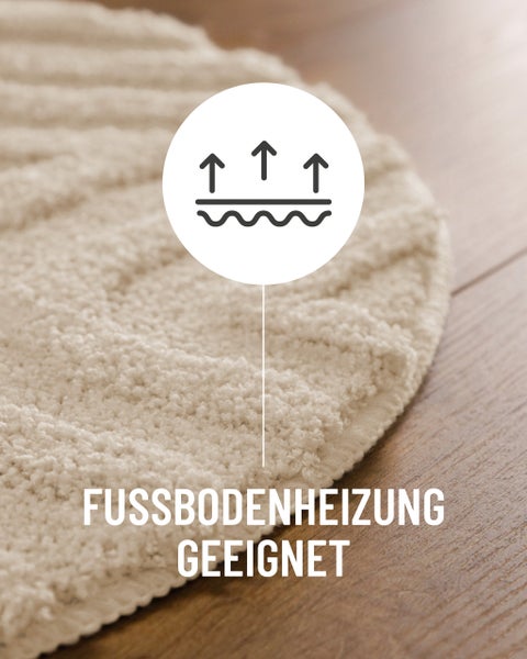 Graue Badematte mit Reliefmuster aus Streifen und Halbkreis auf hellem Holzfußboden vor einer weißen freistehenden Badewanne im Badezimmer.