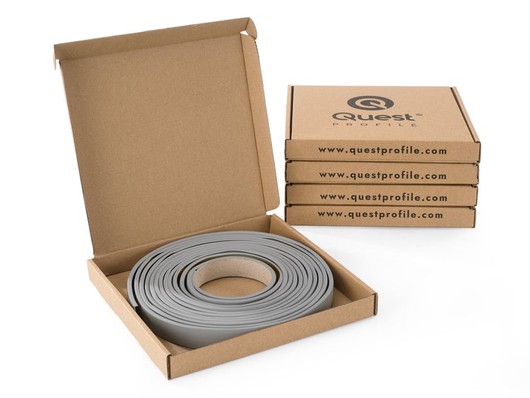 Quest Profile Sockelleiste in geöffneter Verpackung, daneben drei gestapelte, ungeöffnete Verpackungen