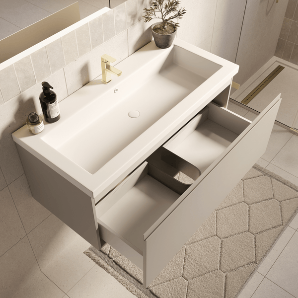 Moderner wandhängender Waschtischunterschrank mit weißem rechteckigem Waschbecken, goldener Armatur und offener Schublade mit Inneneinteilung.