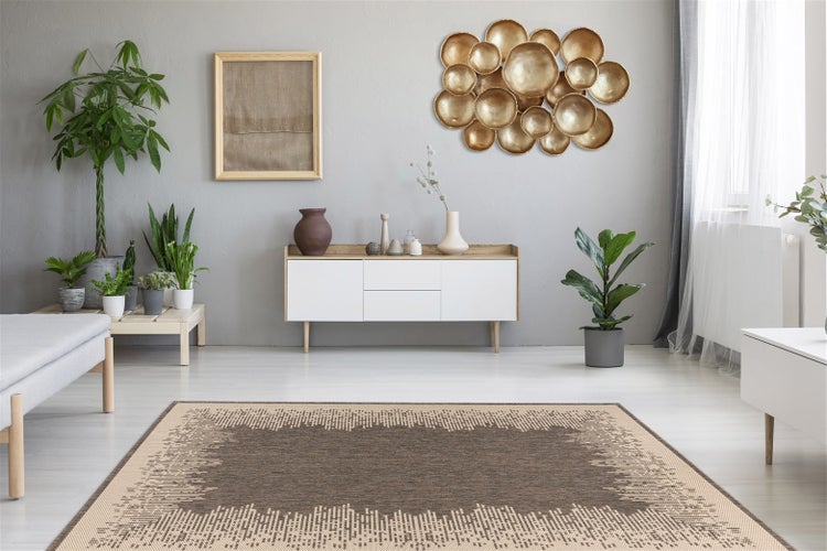 Modernes Wohnzimmer mit braun gemustertem Teppich, weißem Sideboard, goldener Wanddekoration und verschiedenen Zimmerpflanzen.